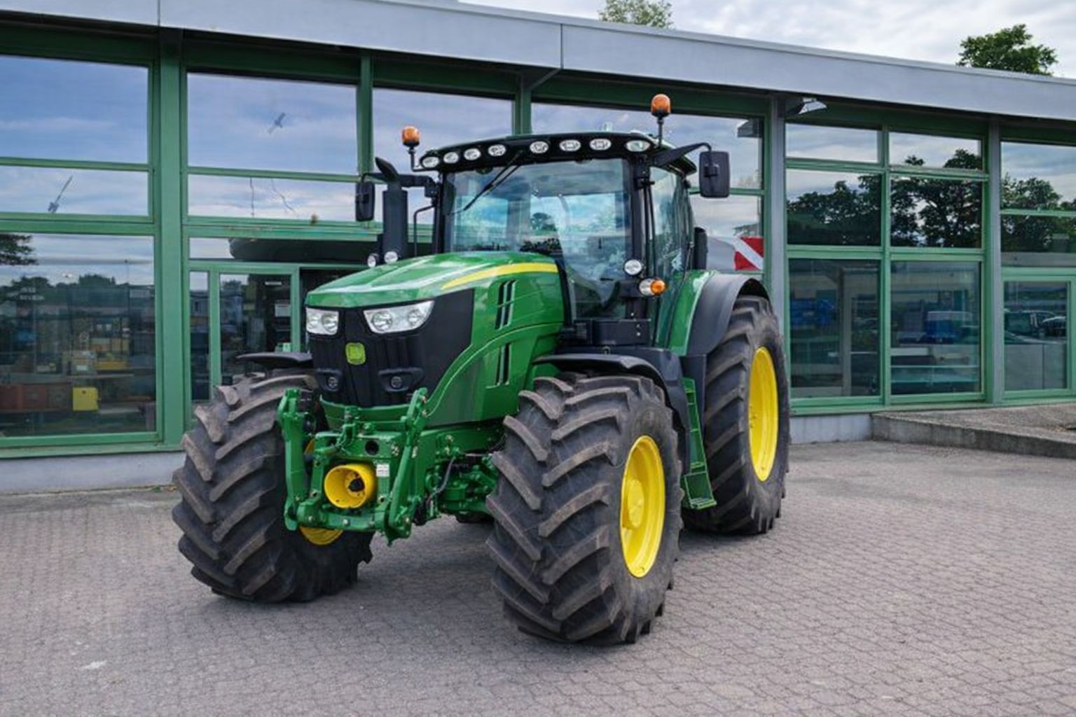 Grüner John Deere Traktor Vor Einem Verkaufsgebäude.