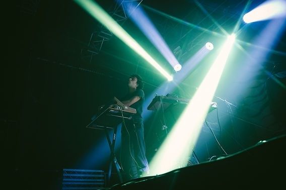 Musiker an Keyboard und Mikrofon im farbigen Bühnenlicht